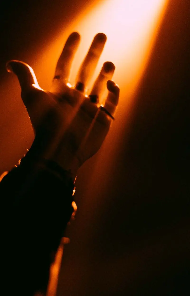 Raised hand in an orange beam. Photo by Iheb Fehri