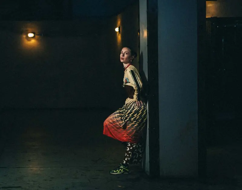 Woman leaning on a pillar in a dark corridor, Camille Doe, Mia Mao Club, 2026. Photo by Iheb Fehri